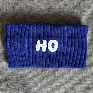 Close-up of deep blue knitted headband featuring white HO letter embroidery patch