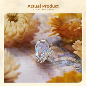 Macro shot of 925 sterling silver dragonfly charm with iridescent blue opal gemstone