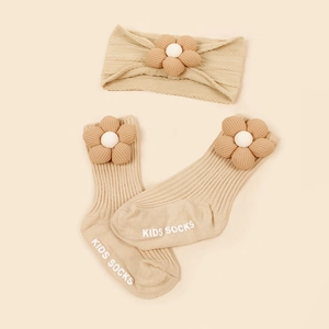 Détail macro du lot de chaussettes et bandeau bébé en maille beige avec fleurs 3D