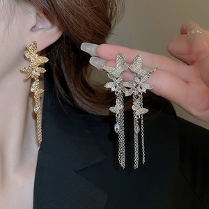 Close-up of golden butterfly earrings with crystal tassels and silver needle details