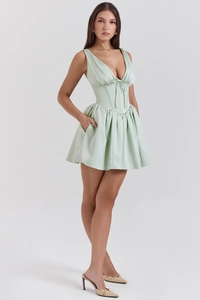 Detail of mint green satin mini dress showing corset waist and pleated skirt with pockets