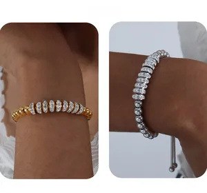 Détail de bracelets perlés or et argent avec disques pavés de cristaux et fermoir réglable