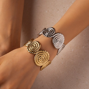 Détails macro des bracelets ouverts dorés et argentés avec motifs en relief spirale