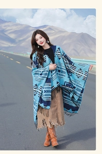 Close-up of ethnic pattern weaving and fringe details on the blue oversized shawl cape