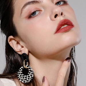 Gros plan de boucles d'oreilles géométriques à motifs à damiers sur un mannequin femme