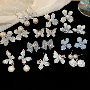 Blue butterfly pearl crystal earrings set with silver needles on black background
