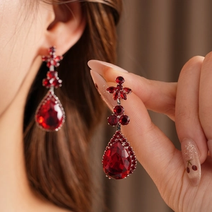 Detail of red pear-shaped zircon floral earrings on model with vintage luxury design