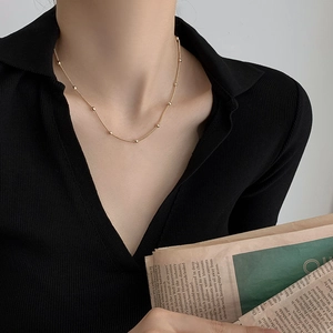 Collier élégant à billes en acier titane doré pour femme porté par un mannequin