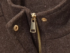 Detail of brown wool jacket featuring high-quality gold zipper and snap buttons