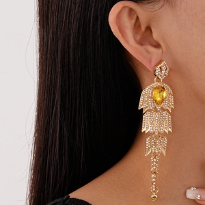 Close-up of vintage gold tassel earring with faux pearls and drop-shaped yellow gemstone