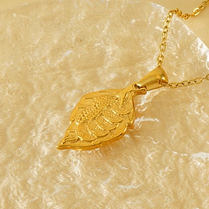 Detailed view of leaf pendant necklace with embossed gold coin design in gold finish