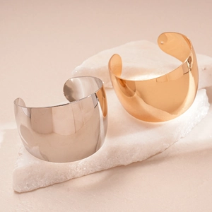Detailed view of wide polished gold and silver cuff bangles on white crystal stones