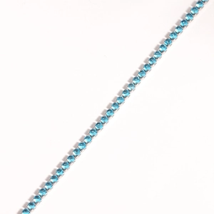 Macro shot of silver tennis bracelet featuring a row of vibrant blue round zircons