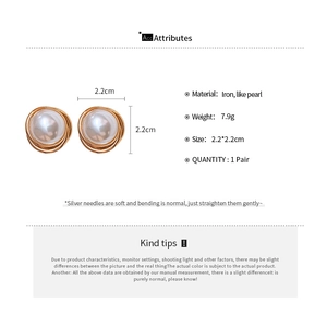 Detailed view of vintage round faux pearl earrings with golden wire wrap and silver needles