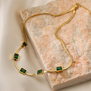Gold snake chain necklace with five square emerald green zircons on beige silk
