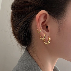 Three-piece gold hoop earring set in minimalist glossy finish shown on model