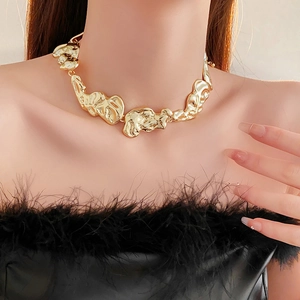 Detail of chunky irregular golden liquid metal necklace on model with black feathers