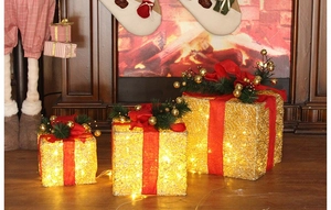 Set of three golden Christmas LED gift boxes with red bows and pine needle decorations