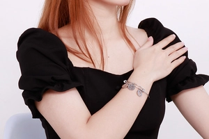 Detail of adjustable silver steel bracelet featuring Love pendant on a model's wrist