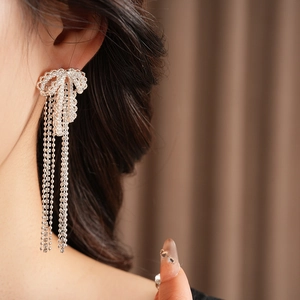 Close-up of sparkling silver zircon bowknot tassel earrings worn by a model