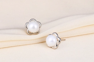 Macro detail of S925 silver flower stud earrings featuring natural freshwater pearls