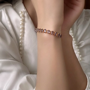 Adjustable gold bracelet with oval purple zircon stones worn over white silk blouse