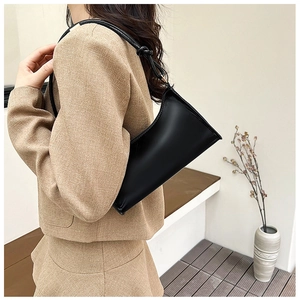 Detail view of a black baguette bag with stylish knot strap on a model shoulder