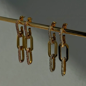 Golden link drop earrings with pink and clear crystals on a display stand