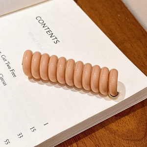 Gros plan d'un élastique spirale beige brillant sur une page de livre, style épuré