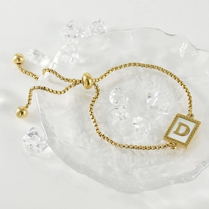 Gold stainless steel alphabet D shell bracelet with adjustable slider clasp on glass