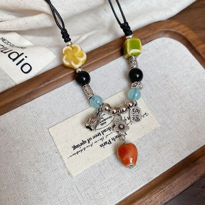 Detail of a vintage Chinese ceramic necklace with colorful beads and a Na Fu bell charm