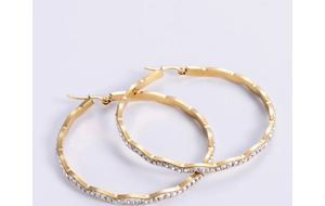 Macro shot of large golden hoop earrings with wavy texture and sparkling rhinestone inlay