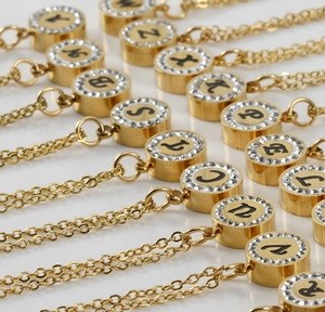 Vue macro de pendentifs en acier doré 18 carats avec cristaux et lettres initiales