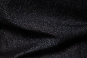 Macro detail of black cotton denim fabric showing high-quality twill weave texture