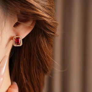 Close-up of a model wearing a red square gemstone earring with small diamond border