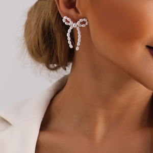 Detailed view of handmade pearl bow earrings worn by a model in a side profile