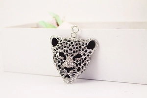 Detailed view of silver leopard head keychain with rhinestones resting on a white gift box