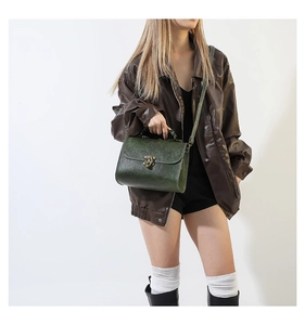 Close-up of green embossed leather crossbody bag with vintage floral pattern and gold clasp