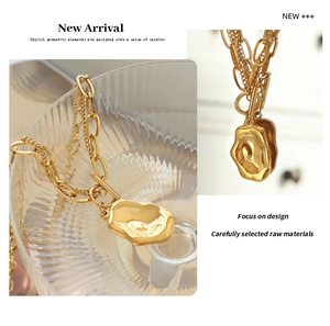 Macro detail of gold layered necklace featuring a molten textured irregular pendant