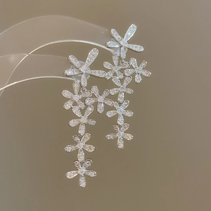 Close-up of silver tassel earrings with flower designs and sparkling zircon stones