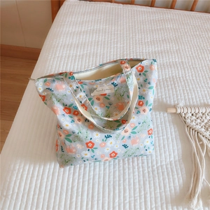 Detailed close-up of light blue floral cotton tote bag with zipper and textile label
