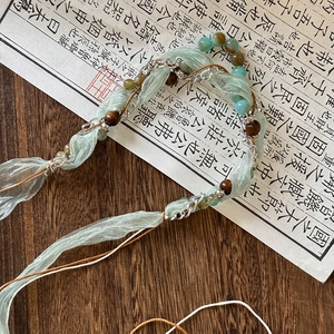Close-up of Bohemian necklace with green silk ribbon, natural stone beads and wood accents