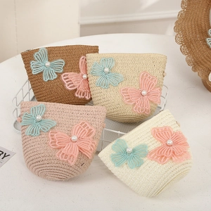 Close-up of woven straw bags with mesh butterflies and pearls in summer colors