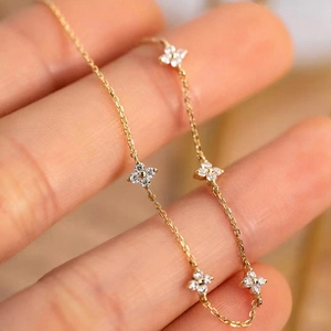 Elegant gold clover bracelet with sparkling zircons and delicate chain on female wrist