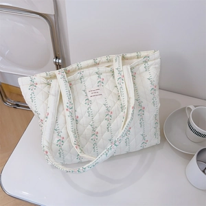Détail du sac cabas matelassé avec motif floral rose et étiquette en tissu rectangulaire
