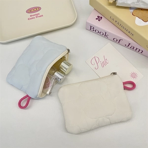 Detail of heart-quilted fabric storage pouch with zipper closure and hanging loop