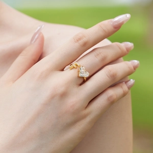 Close-up of golden adjustable ring with T-letter and heart-shaped zircon on finger