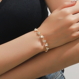Dettaglio di un elegante bracciale ondulato dorato con strass brillanti al polso