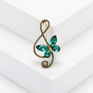 Vintage gold treble clef brooch with emerald butterfly rhinestone on white background