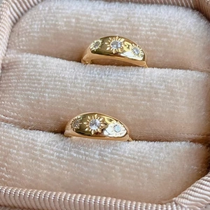 Macro shot of gold-plated starburst pattern rings with cubic zirconia in a velvet box